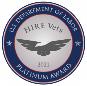 A Silver medallion surrounded by blue. Text says "U.S. Department of Labor HIRE Vets 2021 Platinum Award with an eagle in the center.