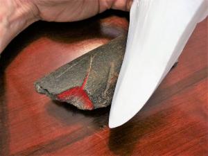 Fossil whale rib with replica Megalodon tooth showing multiple tooth scores from being bitten, and where the rib shattered.