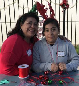 Woman and girl wear Christmas reindeer antlers and make crafts together
