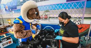 Los Angeles Rams mascot Rampage and APCH staff member packaging bags of groceries