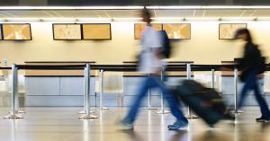People are guided through an airport queue with retractable belt stanchions