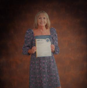 Mauve Group's CEO Ann Ellis stands with her Certificate of Accreditation