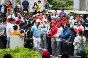 Chinese golfer Wu Ashun walking through the middle of a crowd of golf fans