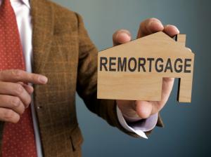 Man points to remortgage written on a wooden house