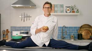 Celebrated Chef Rick Bayless is shown doing the splits on his prep table.