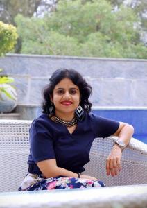A smiling beautiful lady (Sudiptaa Paul Choudhury) in blue formal top and floral printed skirt