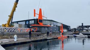 Saildrone Explorer hanging from crane being lowered into the water.