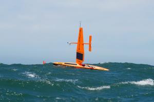 Saildrone Explorer uncrewed surface vehicle sailing in waves on a sunny day in the Pacific Ocean.