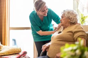 woman helping elderly woman in her home