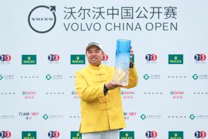Chinese male golfer Jin Zhang wears a golden jacket and holds the Volvo China Open trophy