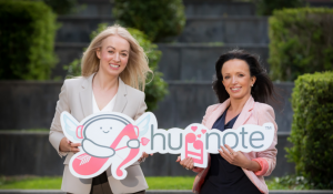 Huggnote founders and sisters holding an image of the Huggnote App logo - which depicts two music notes facing each other as if hugging