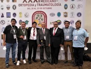 El Dr. García sosteniendo el reconocimiento FEMECOT 2021, rodeado de colegas