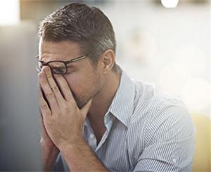 A concerned man rubs his face. Most people get denied Social Security Disability benefits. Disability lawyers can help applicants avoid mistakes.