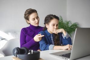 What vitamins should a teenage girl take daily. Teenage girl doing research online for information about vitamins, with mother helping her