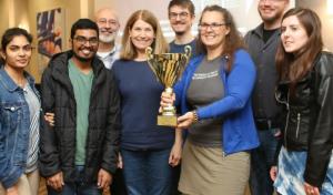 4 men, 4 women gather and smile as they lift the AIR trophy