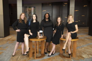 Five attorneys wearing all black posing and smiling