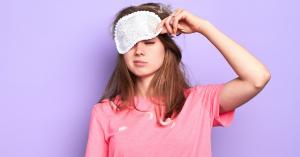 Young girl in tee-shirt with sleeper eyeshades still tired as her circadian rhythm may be off due to low light exposure in winter times.