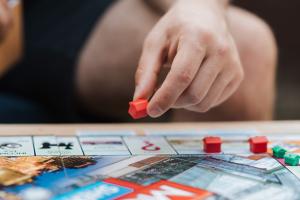 Hand placing a red model house on a monopoly board