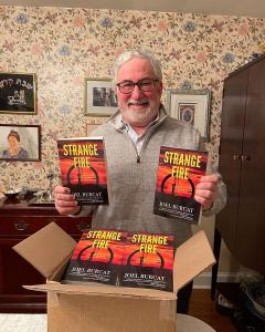 Author and Environmental Attorney Joel Burcat Poses With Copies of His Book STRANGE FIRE.