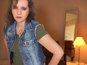 A close up picture of Kalliopi taken at a photo shooting session in a home studio of a friend, with a lamp creating an amber colored ambience and warmth and a standing mirror also used in the background as decor