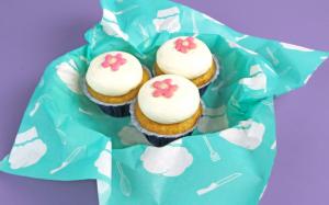 An image of cupcakes sitting on a sheet of custom food paper featuring a chef-themed design in teal and yellow.