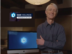 photo of Dan Hollings with the logo for The Plan standing beside a computer