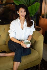 SAYURI founder Yureeka Yasuda holding a cup of matcha on a sofa