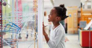 Girl in a science lab looking at science robotics equipment in awe.