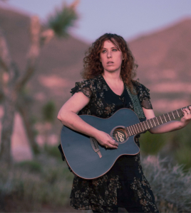 Independent music artist Aliza Hava playing guitar during sunset in a different angle.