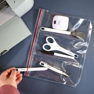 A clear plastic binder page with a hand inserting crafting tools