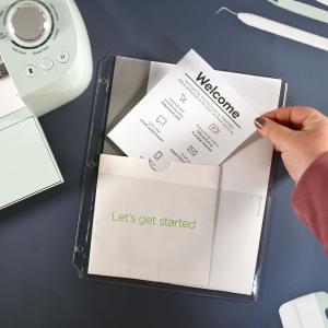 A hand inserting pamphlets, instructions and such into a binder page.