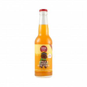 A soda bottle for Soda Dog, a craft sodas for dogs, in Apple and Carrot flavor. The bottle has a label with an illustration of a shaggy dog covering most of it, but the bottle beck is clear showing an orange coloured liquid.