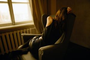 Depressed woman curled up in a chair.