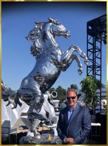 Mark Russo next to 10' tall stainless steel rearing stallion by lorenzo ghiglieri at gordon mccalls motorworks revival in monterey ca
