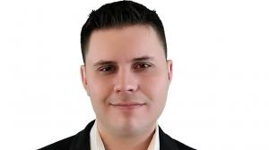 Mark Slapinski stands in front of a white background.