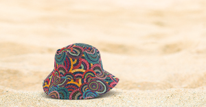 Women's Body Dreaming Bucket Hat on sand - Dreaming by Australian Aboriginal Artist, Cindy Wallace. Cindy is a well-known artist from Santa Teresa, a place about 80km from Alice Springs, Northern Territory, Australia.