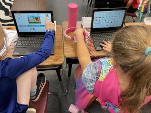 Two young girls with their laptops coding a project.