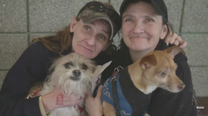 two homeless women holding their small furry dogs