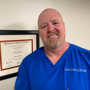 Denver TMJ and Sleep Apnea dentist Dr. Berry standing in front of his Master's Degree making him an Orofacial Pain Specialist