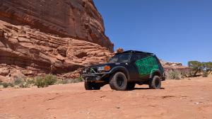 The electric powered land cruiser poses in front of a large red rock cliff face in Moab, Utah