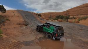 The electric 4x4 crawls through a mud puddle and up onto a steep rock incline