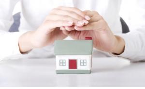 hands covering over rubber home to symbolize home insurance protection