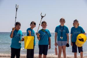 Students pose with their cleanup tools and show the trash they removed
