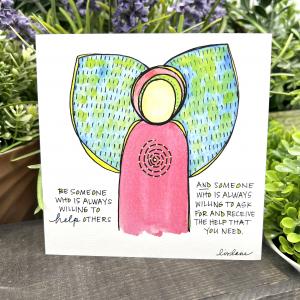 A WingTips print is displayed near houseplants. A bright watercolor angel sketch is beside handwriting that reads, "Be someone who is always willing to help others AND someone who is always willing to ask for and receive the help that you need.” Signed, Liv Lane