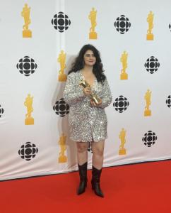 Hill Kourkoutis standing on red carpet holding her Juno Award