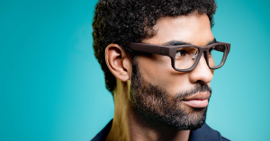 The image shows a man wairing a pair of tooz smart glasses that have a slim and stylish form factor, and thus look and function like normal eyewear for all-day use.