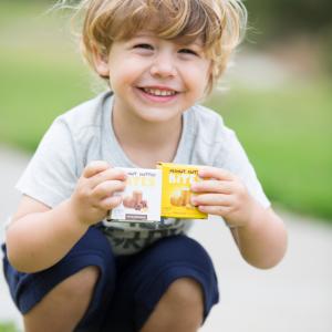 A toddler holds two boxes of Pasokin Peanut Butter Bites