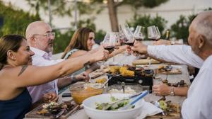 The Doffo Family clinks glasses of wine in a toast with Family Dinner Host Andrew Zimmern