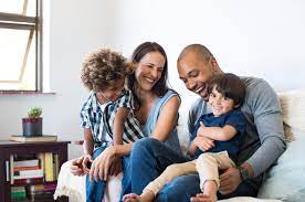 A mix race couple and two children seating on a couch