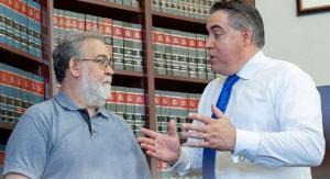 Fred Sommer, an attorney at Horenstein, Nicholson & Blumenthal (HNB) law firm in Ohio, talks to a client in a conference room filled with law books. HNB helps Ohioans with workers' compensation claims.